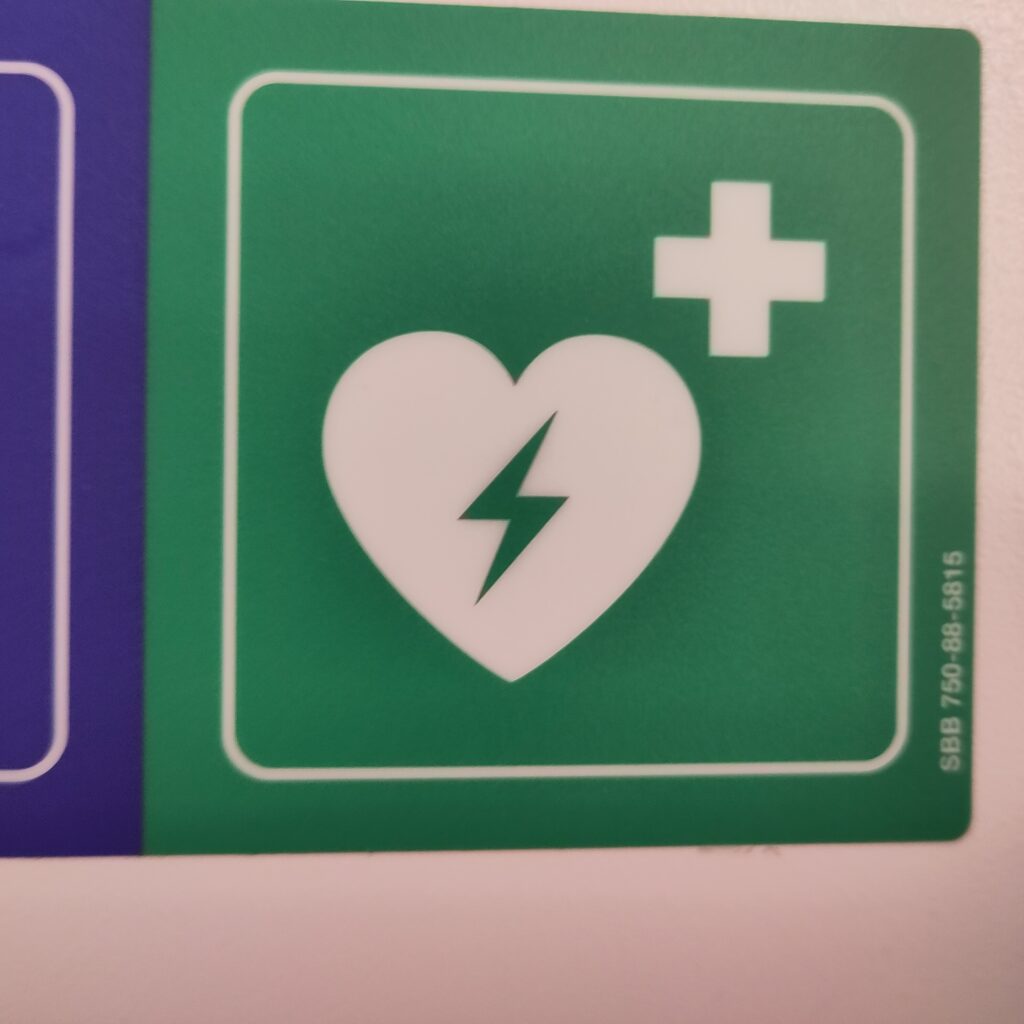 Herz mit Blitz und weisses Kreuz auf grünem Grund.